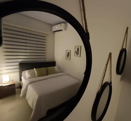 1 dormitorio con cama y espejo redondo en BHB - ApartaHotel, en Leticia