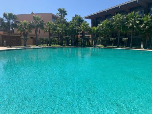 a large blue swimming pool in front of a building at Salgados - Vila das lagoas, Beach & Golf in Albufeira