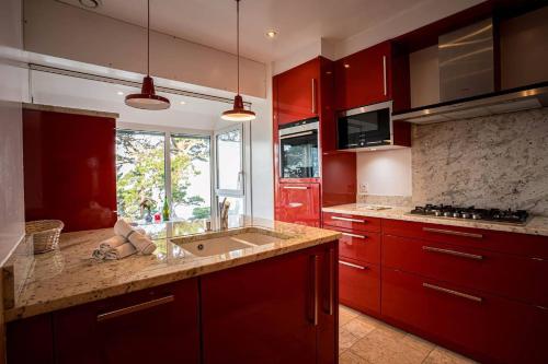 une cuisine avec des armoires rouges et un évier dans l'établissement La loge, La Loge House overlooking the sea in Per, à Perros-Guirec