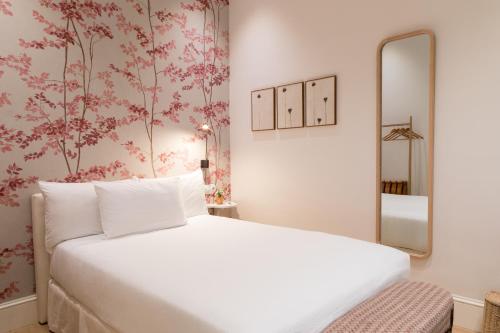 塞维利亚Hotel Tayko Sevilla的卧室里有一张白色的床和一面镜子