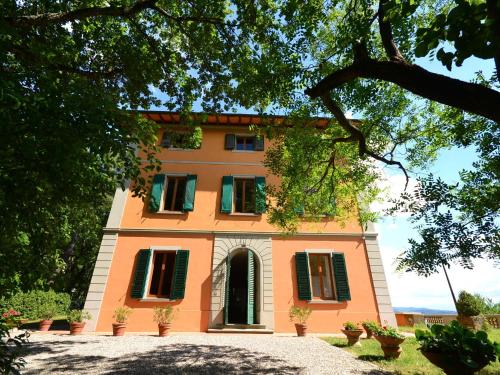 um grande edifício laranja com persianas verdes em Lovely holiday home in Montefiridolfi with hill view em Montefiridolfi