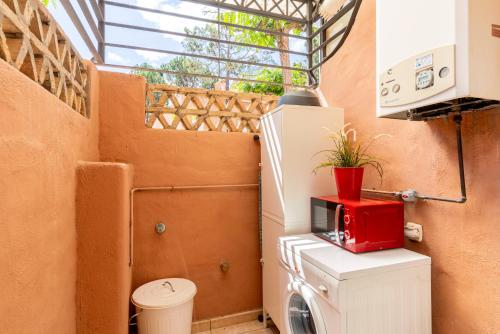 - une petite salle de bains avec un four micro-ondes rouge au-dessus d'un lave-linge dans l'établissement ALTAVISTA ISLANTILLA GOLF by MSHOLIDAYS, à Islantilla