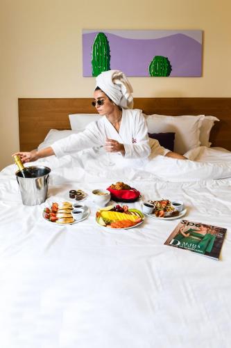 una donna seduta a letto con piatti di cibo di The Smallville Xpress a Beirut