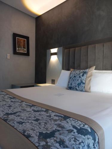 a bedroom with a large bed with a blue and white blanket at PULA NALA LODGE in Rustenburg