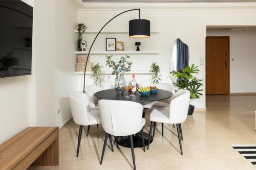 a dining room with a black table and white chairs at Champagne Sea View Apartment by BiNoBi! in Thessaloniki