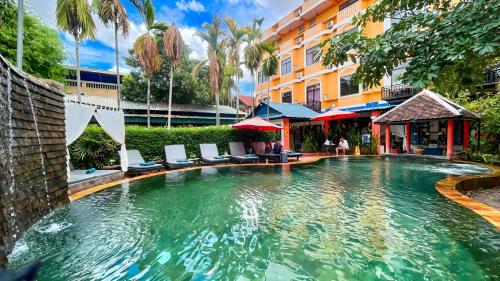 une piscine dans un hôtel avec des chaises et un bâtiment dans l'établissement Central Indochine D'angkor Hotel, à Siem Reap