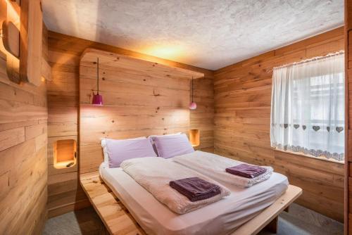a bedroom with a bed in a wooden room at Tana del picchio Rosso in Falcade