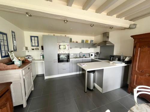 a large kitchen with white counters and appliances at La maison des écuyers avec grand jardin et barbecue in Rônai
