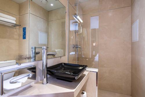 y baño con lavabo y ducha. en Hotel Marena en París