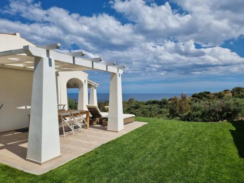 a patio with a pergola and a table on a lawn at Il Borgo Del Mare - BUDONI SWEET HOME in Budoni