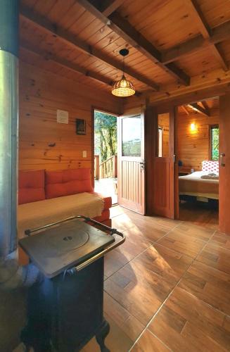 a room with a bed and a stove in a cabin at Pousada Vale da Imbuia chalé para temporada in Urubici