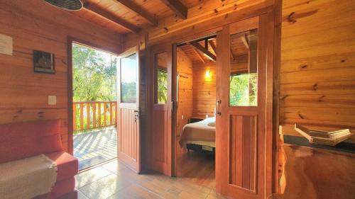 a bedroom with a bed and a door to a balcony at Pousada Vale da Imbuia chalé para temporada in Urubici