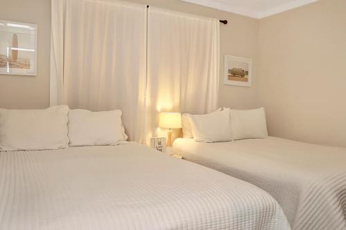 two white beds in a white room with a window at The Surf Ranch by Pristine Properties Vacation Rentals in Port Saint Joe