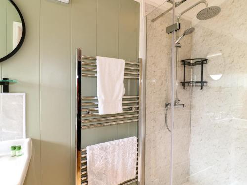 uma casa de banho com um chuveiro, um lavatório e um espelho. em Hazel em Swadlincote