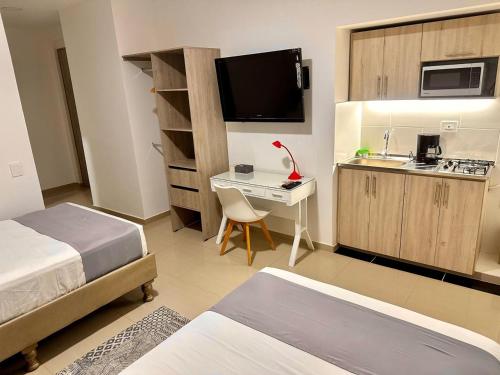 Habitación de hotel con 2 camas, escritorio y cocina en On Apartasuites, en Cali