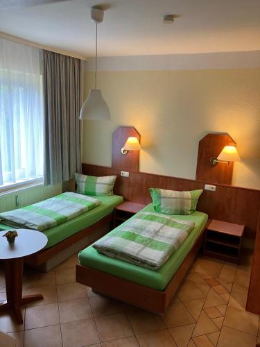 a hotel room with two beds and a table at Chausseehaus - Ferienwohnungen Rottleberode am Harzrand in Rottleberode