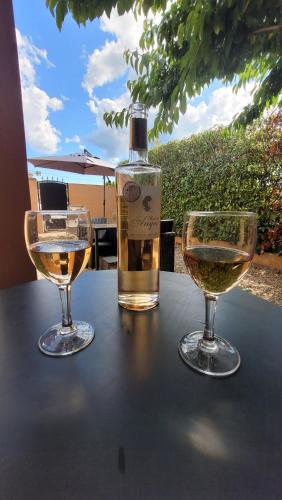 une bouteille de vin et deux verres sur une table dans l'établissement Le petit chez nous Gîte climatisé jardin, à Pignans