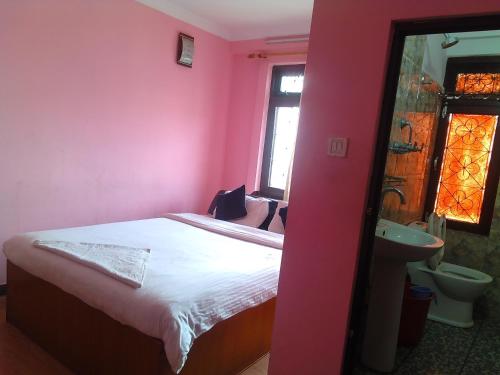- une chambre rose avec un lit et un lavabo dans l'établissement Kathmandu Fawlty Home, à Katmandou