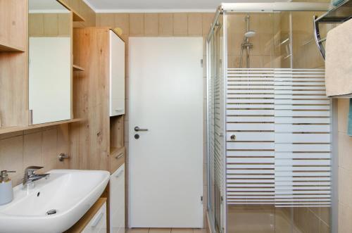 a bathroom with a glass shower and a sink at Ferienwohnung Goesmann in Zetel