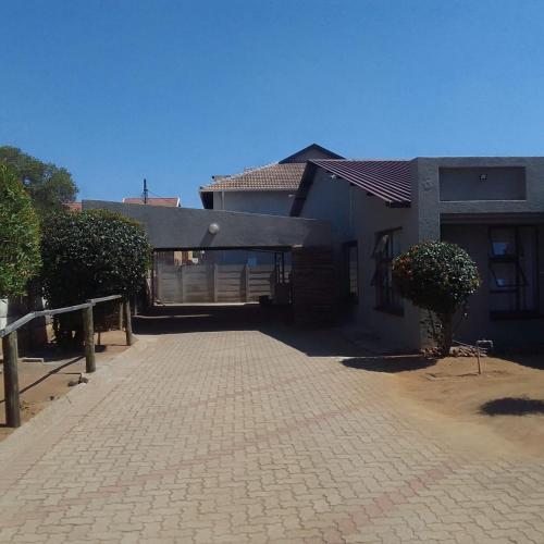 a house with a brick driveway in front of a building at The Best Moments guesthouse in Rustenburg