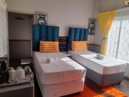 two beds in a room with blue and white at The Best Moments guesthouse in Rustenburg