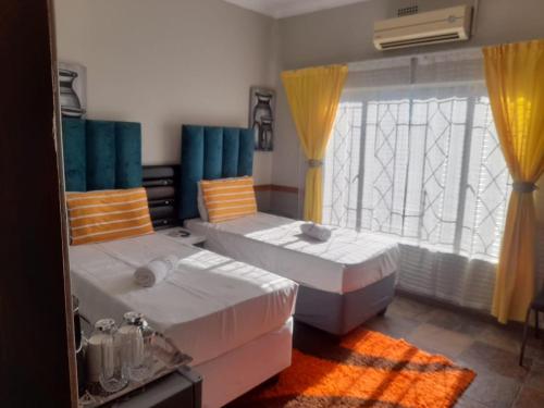 a bedroom with two beds and a window at The Best Moments guesthouse in Rustenburg