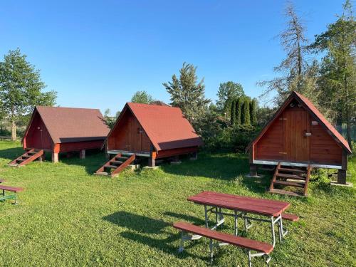 un grupo de tres graneros con mesas de picnic en un campo en SZAŁASY drewniane nad rzeką BIEBRZA en Goniadz