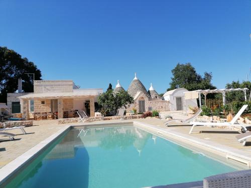 a swimming pool with chairs and a house at Trullo del Sol in Ceglie Messapica