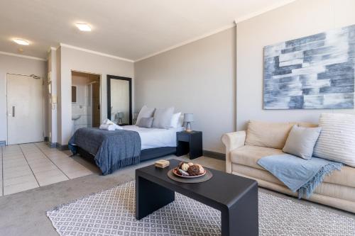 a living room with a bed and a couch at Four Seasons City Apartment ParkingPool Gym in Cape Town