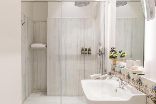 a white bathroom with a shower and a sink at Hotel Tayko Sevilla in Seville