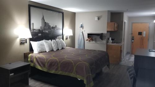 a hotel room with a bed with a picture on the wall at Super 8 by Wyndham Dickson in Dickson