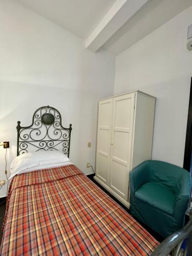 a bedroom with a bed and a green chair at Hotel Beau Rivage in Alassio
