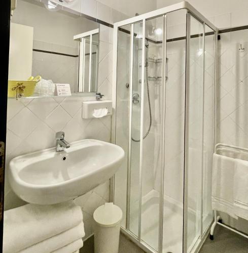 a white bathroom with a shower and a sink at Hotel Beau Rivage in Alassio