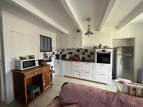 une cuisine avec des armoires blanches et un micro-ondes dans l'établissement Charmant gite de Valérie et de Frédéric MAZA, à Quettreville-sur-Sienne