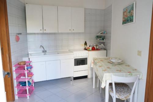 una cucina con armadi bianchi, tavolo e lavandino di FM Apartaments Forio a Ischia