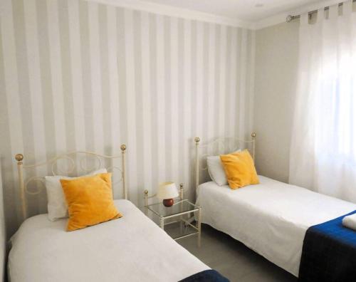 two beds with orange pillows in a room at Lagos Love Bay - sea view in Lagos