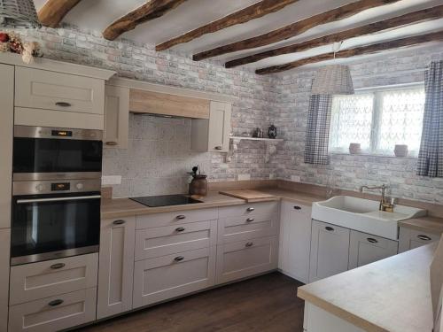 une cuisine avec des armoires blanches et un évier dans l'établissement Gite 7 personnes piscine privée, à Savignac-les-Églises