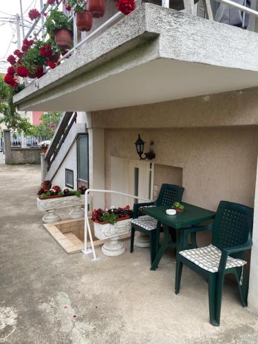 un patio con una mesa verde, sillas y flores en Apartman Tadija Niš, en Donja Vrežina