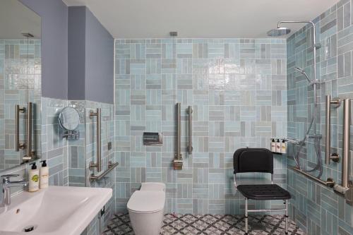 łazienka z toaletą, umywalką i krzesłem w obiekcie Hotel Indigo Coventry, an IHG Hotel w Coventry