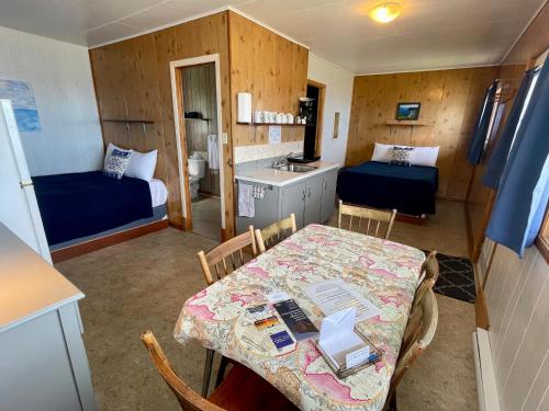 a room with a table and a kitchen with two beds at Chalets Bernatchez in Mont-saint-pierre