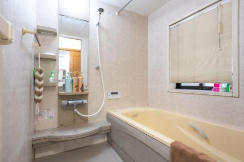 a bathroom with a tub and a shower and a window at 7House in Tokyo