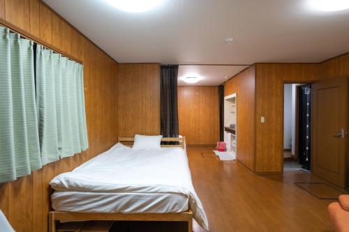 a bedroom with a bed in a room with wooden walls at 7House in Tokyo