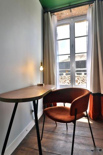une table et une chaise devant une fenêtre dans l'établissement Le25 Parahotellerie, à Montbron