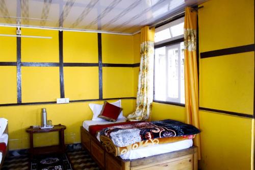 a yellow room with a bed and a window at Heaven valley home stay in Pedong