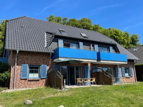 a brick house with a blue balcony and a yard at Ferienwohnung 04 am Selliner See in Ostseebad Sellin