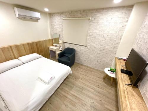 ein Schlafzimmer mit einem Bett, einem Stuhl und einer Tafel in der Unterkunft Fengchia Aliproda in Taichung