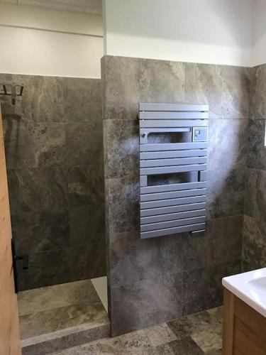 La salle de bains est pourvue d'une douche et d'un mur en pierre. dans l'établissement Le grand Epilly, à Chaumont-sur-Tharonne