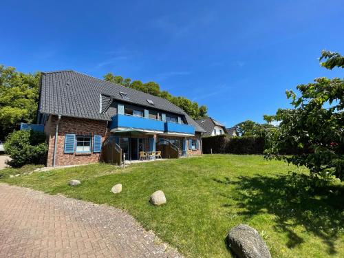 ein Backsteinhaus mit blauen Fenstern auf einem grünen Hof in der Unterkunft Ferienwohnung 02 am Selliner See in Ostseebad Sellin