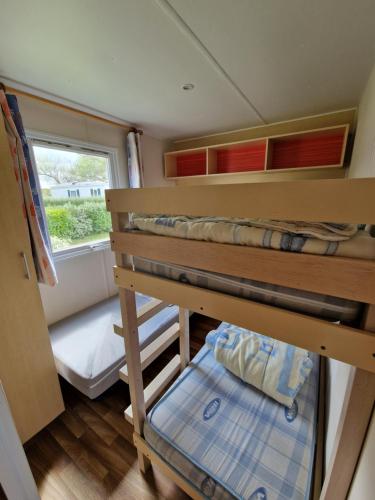 a small room with bunk beds and a window at Mobil home plouescat in Plouescat