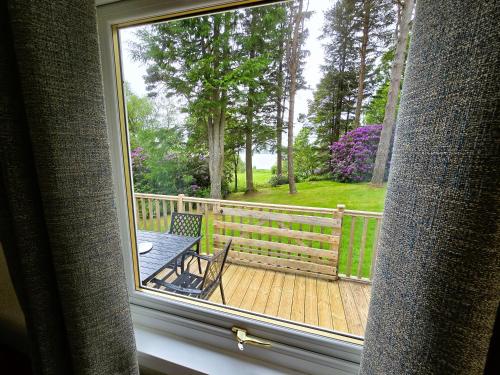 a view from a window of a deck with a chair at Ard Veich Estate - Panoramic Highland Sea Views with private beach and woodland in Port Appin